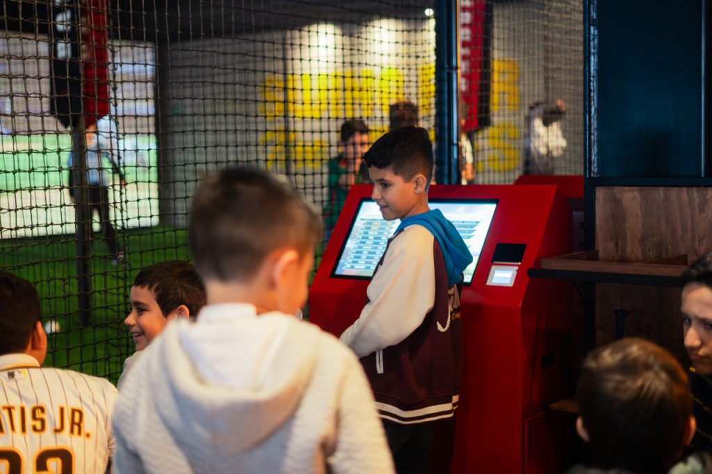 Jóvenes y familias disfrutan de la emoción del béisbol en Batbox, rodeados de la atmósfera de un estadio gracias a los avanzados simuladores.