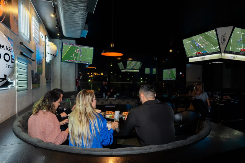 Fanáticos emocionados celebrando durante el Super Bowl en Batbox.